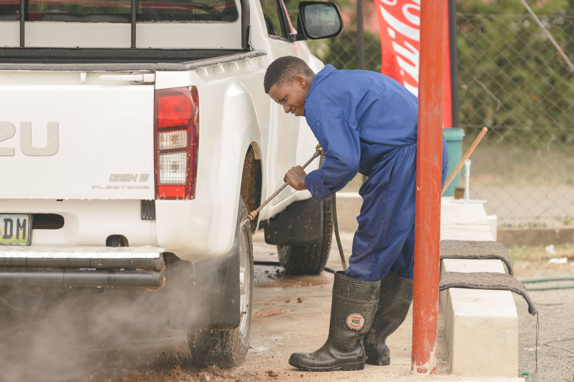 MAPS Village attendant pressure washing the wheel of a bakkie